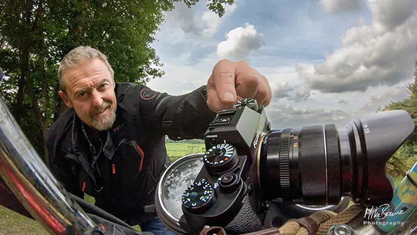 Man wearing motorcycle jacket pointing at a camera